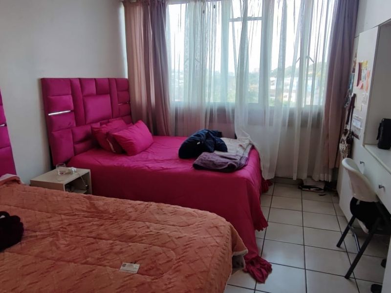 A bedroom featuring tiled flooring, a built-in wardrobe, and a built-in desk area with large windows providing natural light.