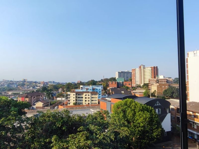 An elevated urban view looking out over the surrounding neighbourhood and city skyline from a window.