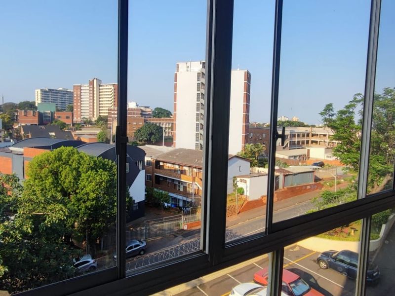 An elevated view of the surrounding urban neighbourhood captured through large aluminium sliding windows.