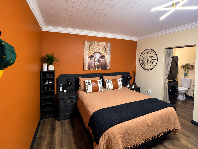 A well-maintained bedroom featuring a tongue and groove ceiling, crown molding, and an integrated laundry closet with direct access to an en-suite bathroom.