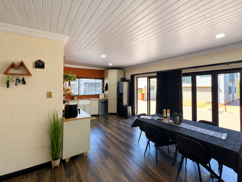 Spacious open-plan kitchen and dining area featuring timber-look flooring, a farmhouse sink, and large sliding glass doors providing seamless access to the exterior.