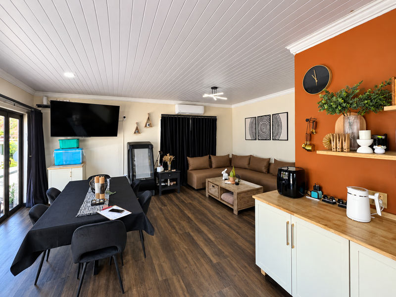 Spacious open-plan living and dining area featuring timber-look flooring, a tongue and groove ceiling, split-system air conditioning, and modern built-in cabinetry.