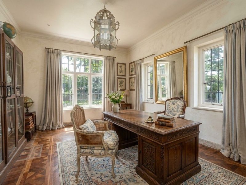 Elegant home office featuring intricate parquet flooring, classic leaded glass windows, and sophisticated crown molding, creating a refined and professional workspace.