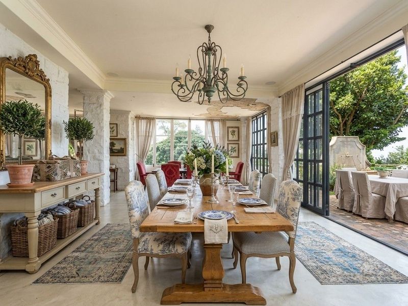 Elegant dining room featuring exposed stone walls, polished concrete floors, and large glass sliding doors that open onto a private patio area.