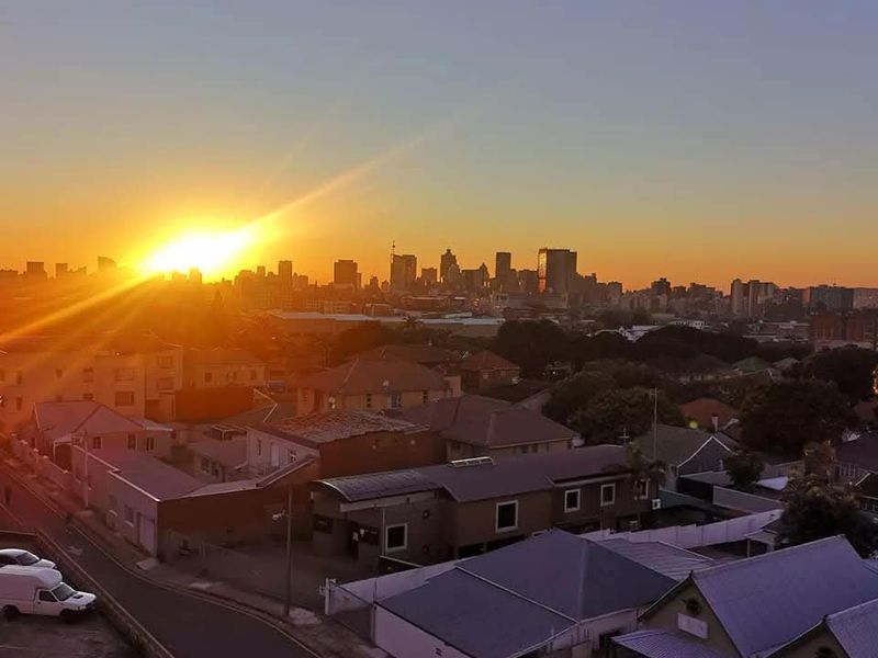 Elevated panoramic view of the city skyline at sunset, showcasing the surrounding urban landscape and residential neighborhood.