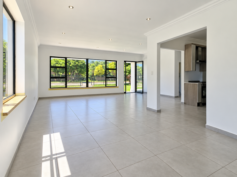 Spacious open-plan living area featuring large windows, modern tiled flooring, recessed lighting, and a seamless transition to a contemporary kitchen space.
