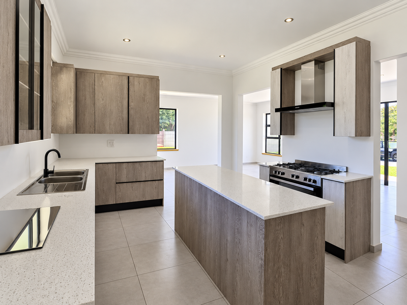 Modern kitchen featuring light wood cabinetry, quartz countertops, a central island, and high-quality built-in appliances, offering a clean and contemporary aesthetic.