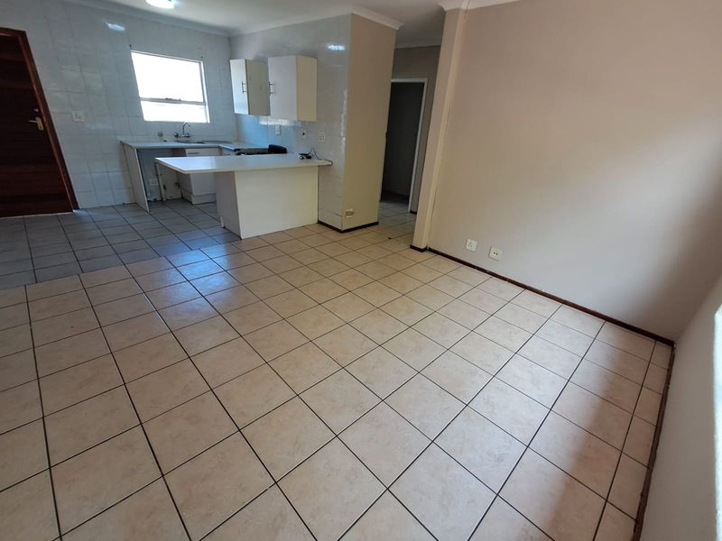 An open-plan living and kitchen area featuring tiled flooring, a breakfast counter, and functional kitchen cabinetry.