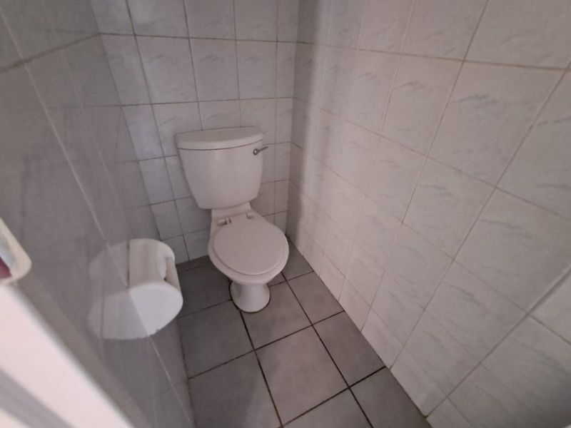 A compact bathroom featuring tiled walls and flooring with a standard toilet fixture.