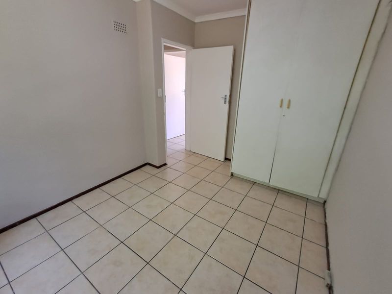 An empty bedroom featuring tiled flooring and a built-in wardrobe, offering a neutral canvas for personalization.