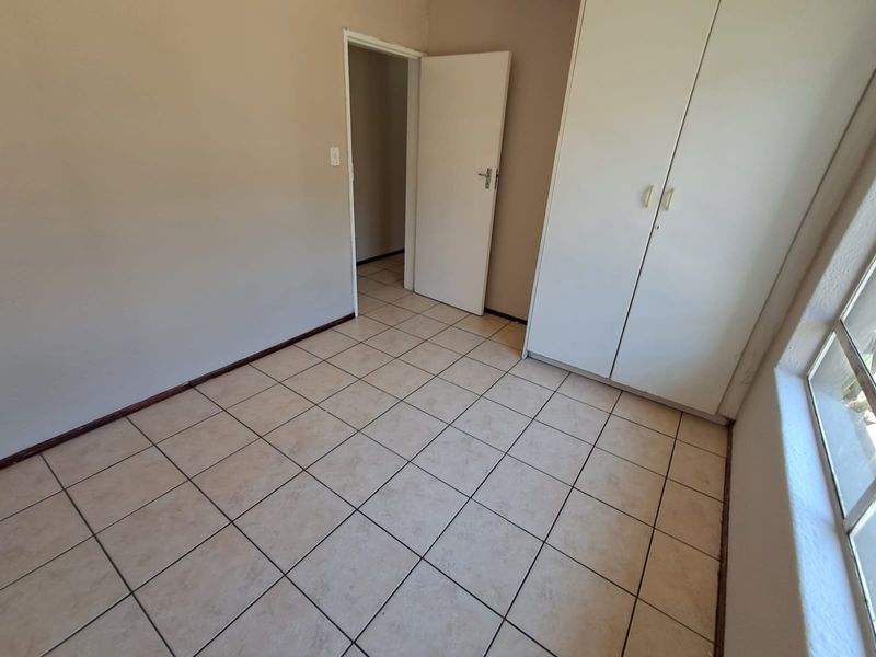 An empty bedroom featuring neutral tiled flooring and a built-in wardrobe, offering a clean and versatile space ready for personalization.