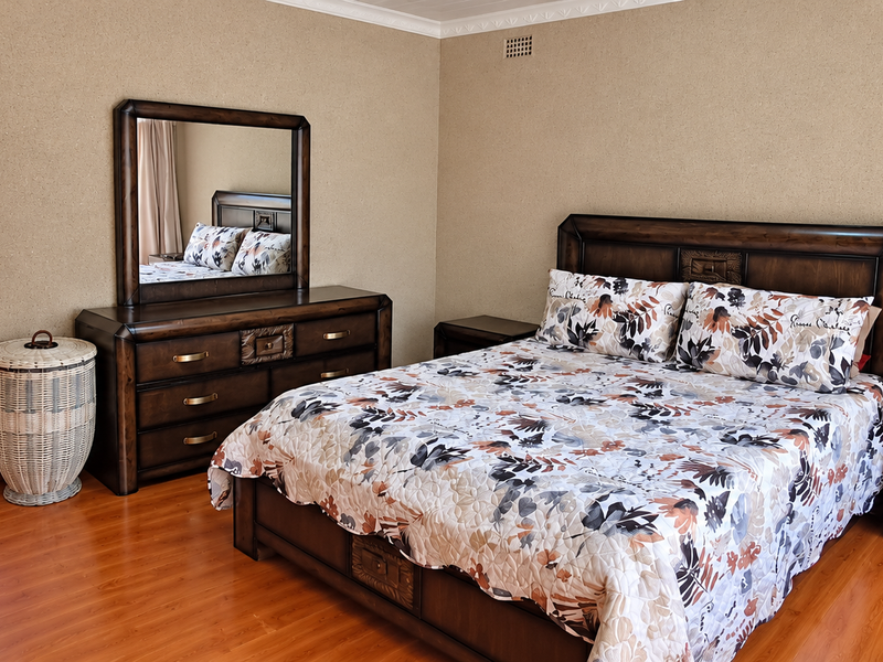 A spacious bedroom featuring laminate flooring, coved ceiling detailing, and a neutral wall finish, providing a comfortable and functional sleeping area.