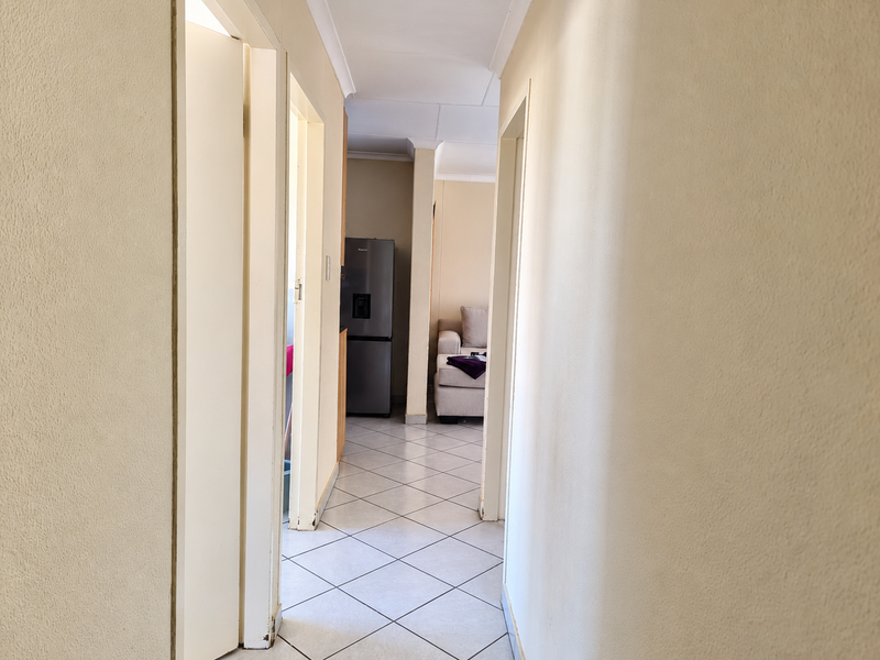 A functional hallway with tiled flooring and neutral walls, providing access to adjacent living areas and kitchen space.