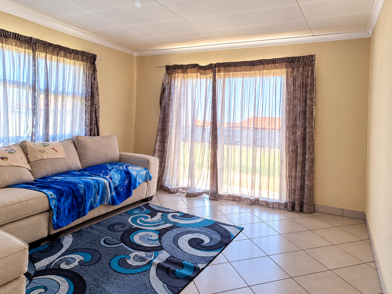 A bright living room featuring tiled flooring and a large sliding glass door that provides access to the outdoor area.