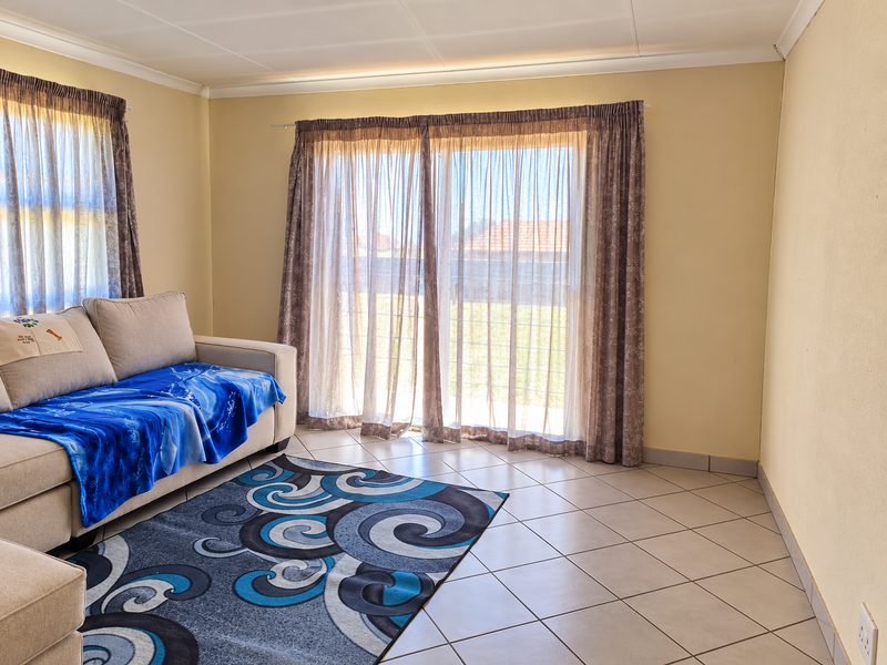 A living room featuring tiled flooring and a large sliding glass door that provides access to the exterior.