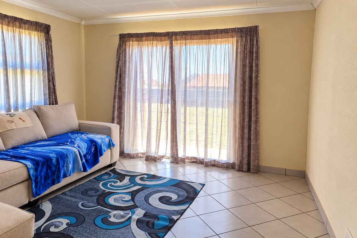 A living room featuring tiled flooring and a large sliding glass door that provides access to the exterior.