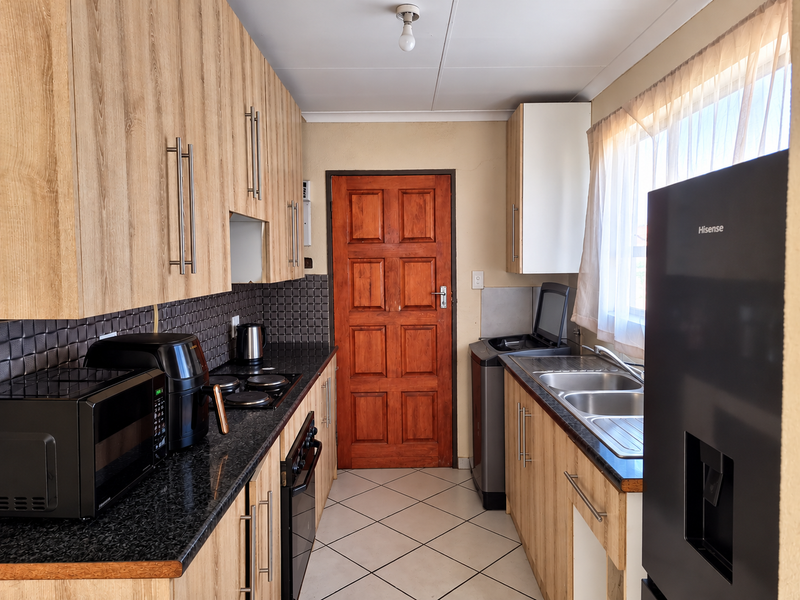 A functional kitchen featuring wood-look laminate cabinetry, granite countertops, a double basin sink, and a built-in oven with hob.