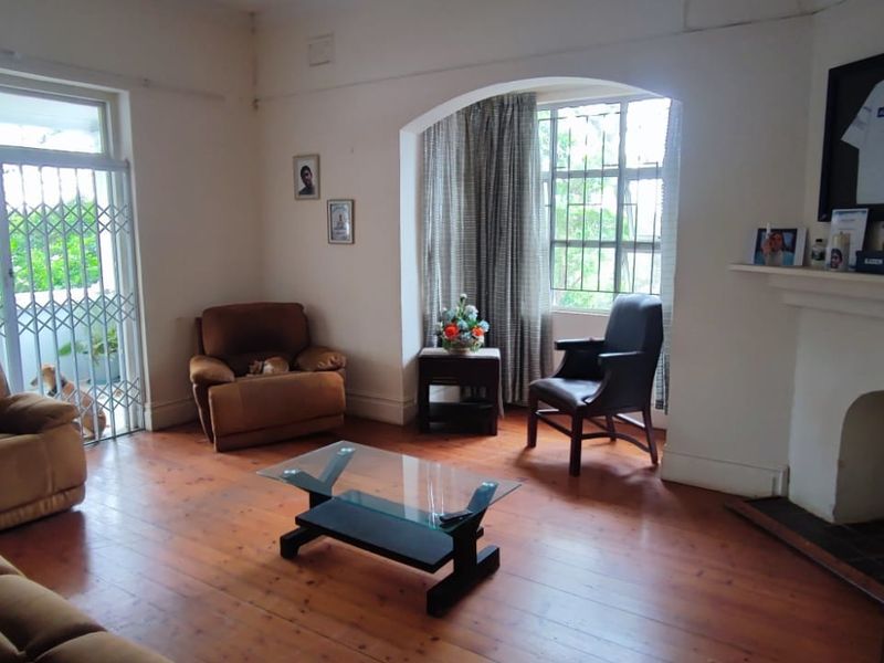 A living room featuring timber flooring, a fireplace with a mantelpiece, and an arched alcove, providing a classic foundation for interior updates.
