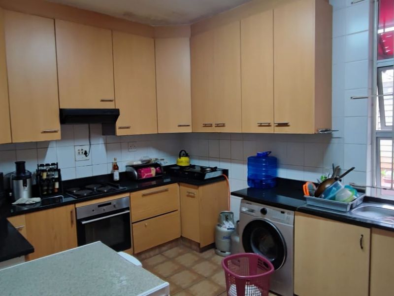 Functional kitchen featuring light wood cabinetry, black granite countertops, built-in oven, gas hob, and a double sink with security bars on the window.