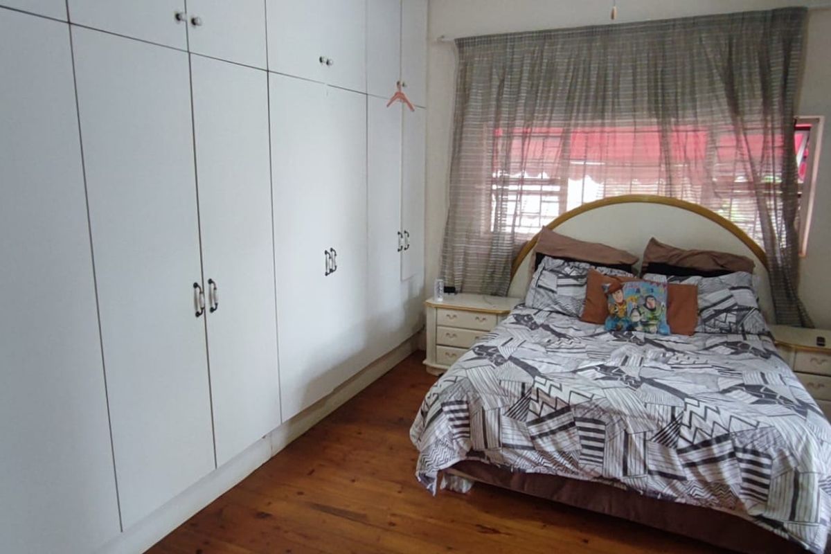A bedroom featuring extensive floor-to-ceiling built-in cupboards and warm timber flooring, providing ample storage and a classic aesthetic.