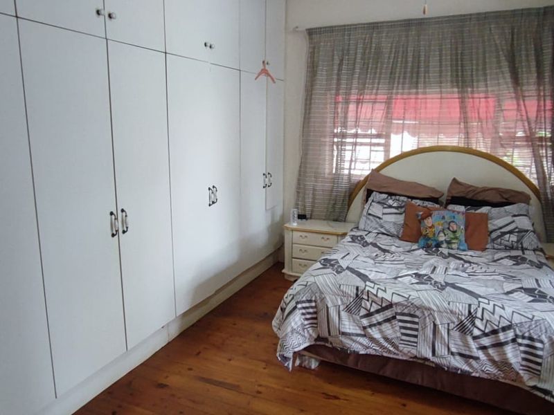 A bedroom featuring extensive floor-to-ceiling built-in cupboards and warm timber flooring, providing ample storage and a classic aesthetic.