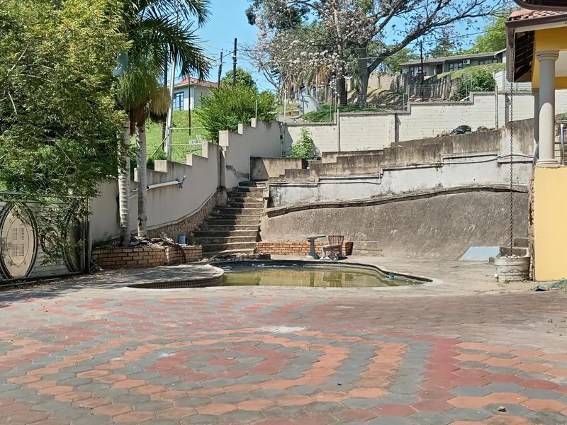Outdoor pool area featuring a paved patio, concrete retaining walls, and stairs, requiring maintenance and refurbishment to restore its appeal.