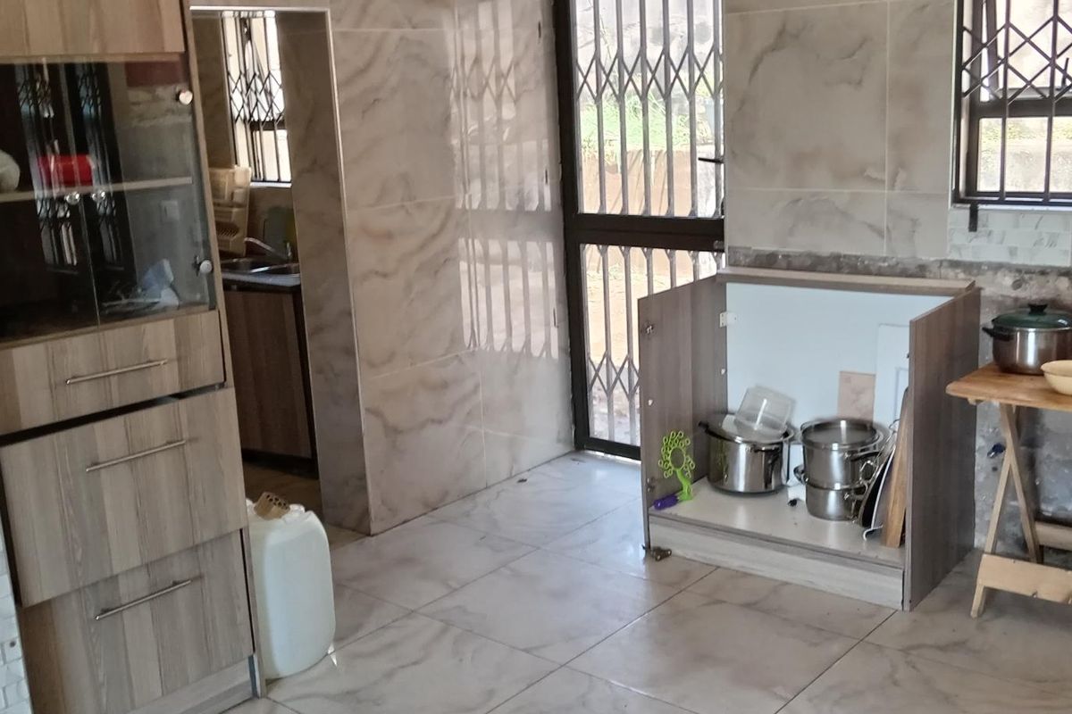 A kitchen area featuring tiled walls and flooring, with visible unfinished wall sections and partially installed cabinetry requiring completion.