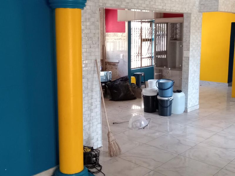 Open plan living area featuring tiled flooring and a decorative column, currently undergoing renovation with unfinished wall sections.