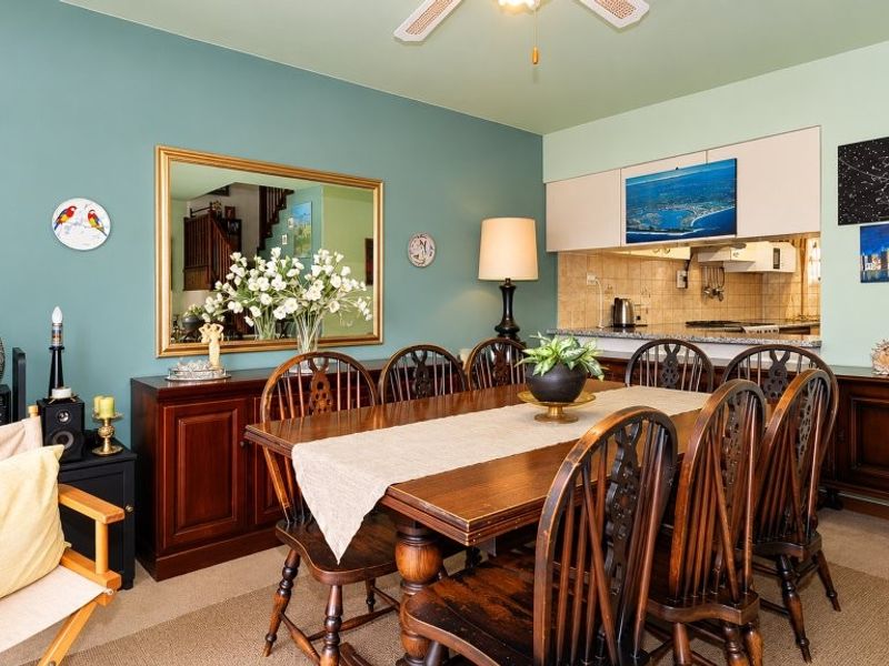 Open plan dining area featuring a ceiling fan and direct access to a functional kitchen with granite countertops and built-in cabinetry.