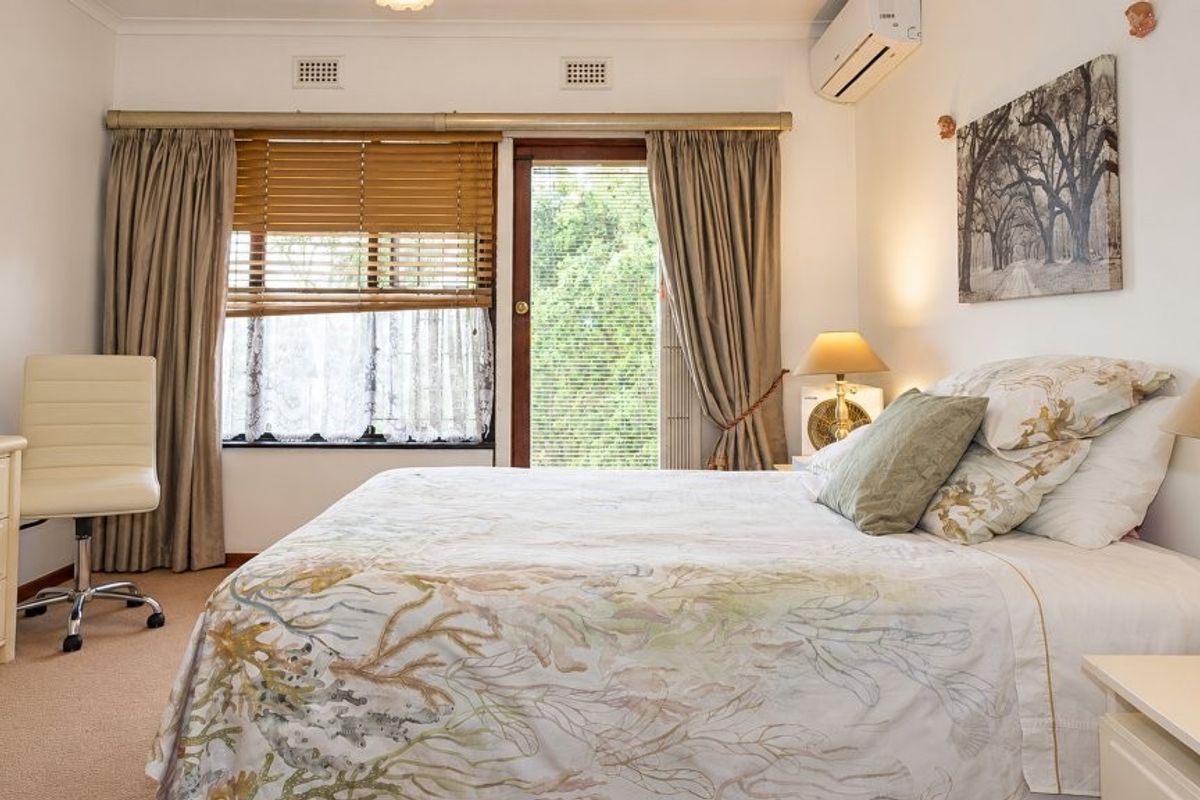 A well-maintained bedroom featuring carpet flooring, a split-system air conditioner, and a sliding glass door providing natural light and outdoor access.