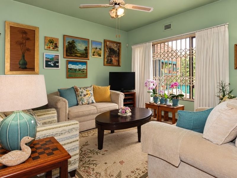 A cozy living room featuring a ceiling fan and a window with a security gate, providing a comfortable and functional space.