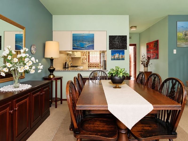 Open plan dining area featuring a staircase with wooden handrail and a pass-through window connecting to the kitchen space.