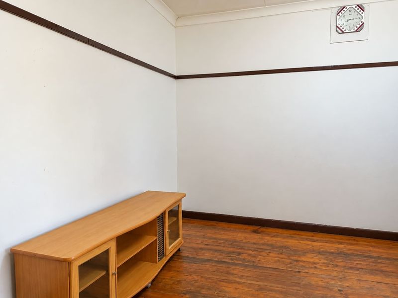 A simple living room featuring original timber flooring, white walls with dark timber picture rails, and classic skirting boards.