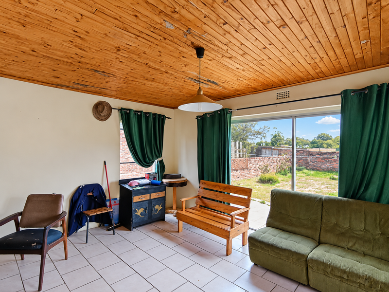 Living room featuring a timber tongue and groove ceiling, ceramic tiled flooring, and a large sliding glass door providing access to the rear garden.