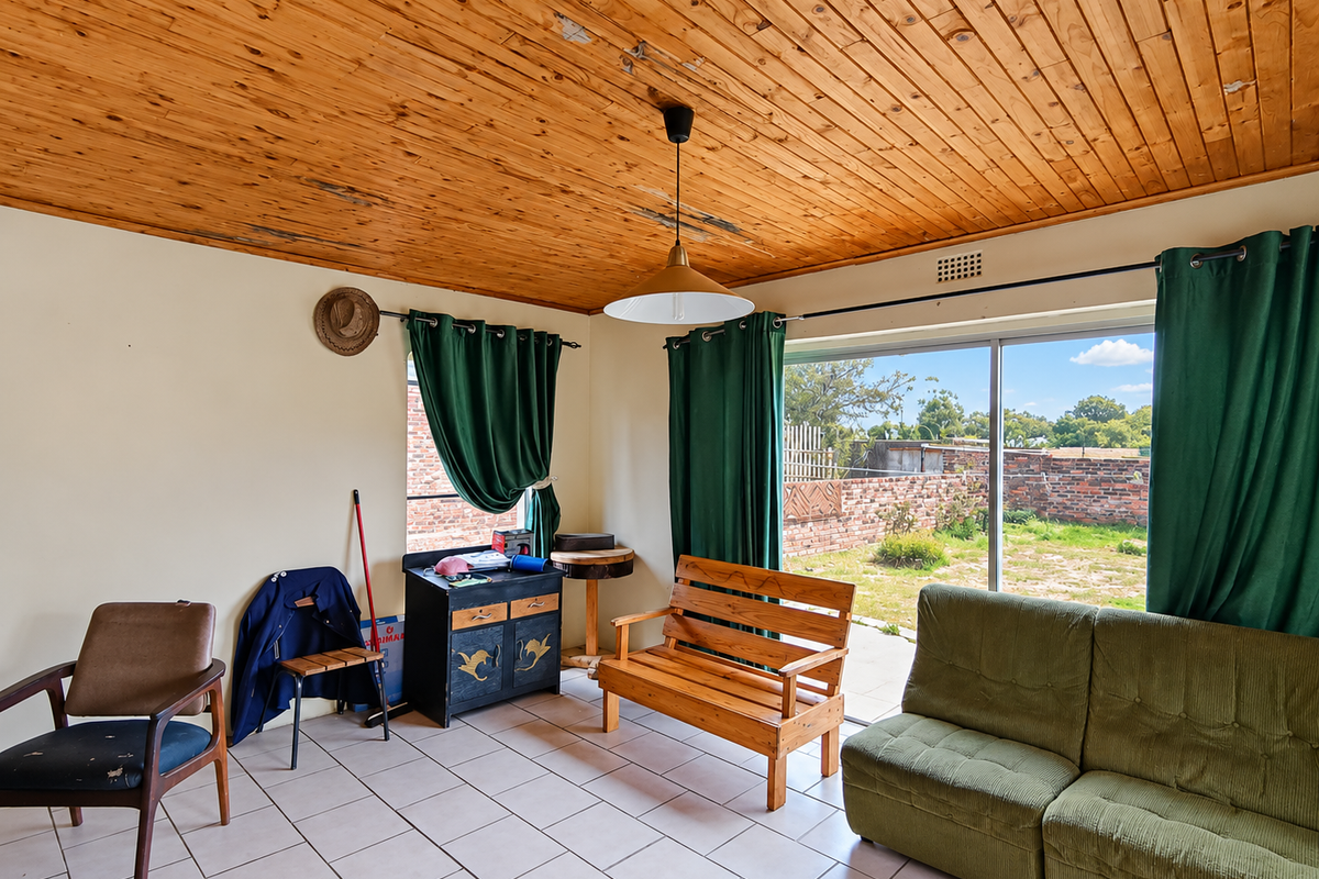 Living room featuring a timber tongue and groove ceiling, ceramic tiled flooring, and a large sliding glass door providing access to the rear garden.