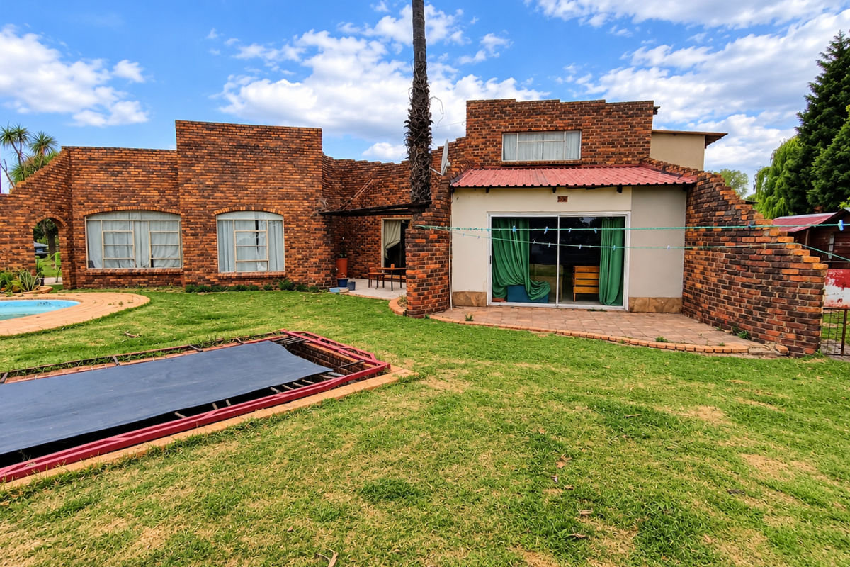 Rear view of a face brick house featuring a swimming pool, paved patio area, and sliding glass doors leading to the interior.