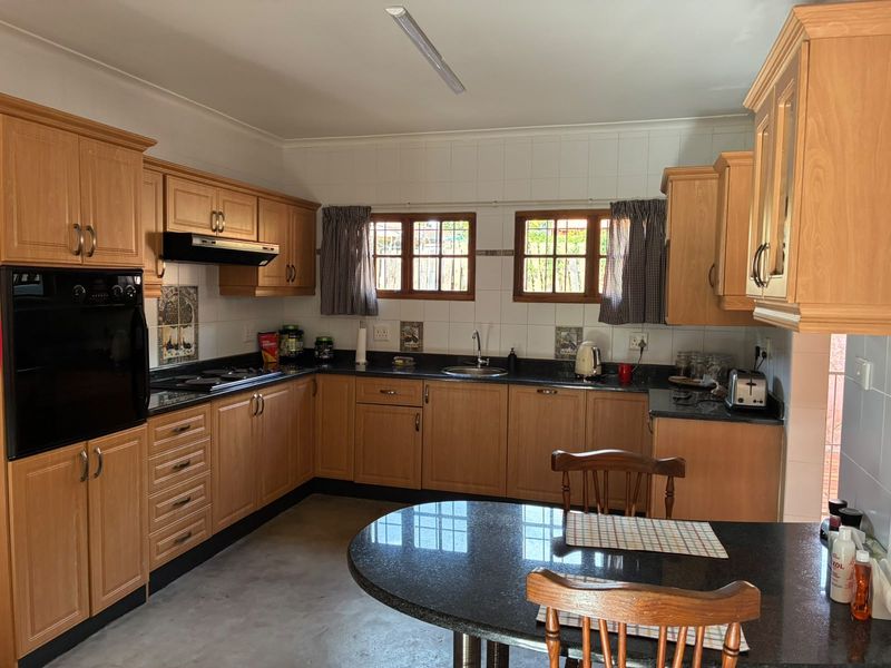 A functional kitchen featuring wood-finish cabinetry, granite countertops, a built-in oven, and a hob, offering a classic layout with ample storage space.