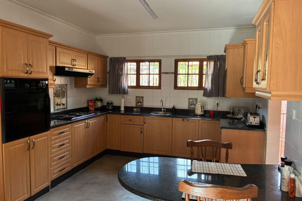 A functional kitchen featuring wood-finish cabinetry, granite countertops, a built-in oven, and a hob, offering a classic layout with ample storage space.