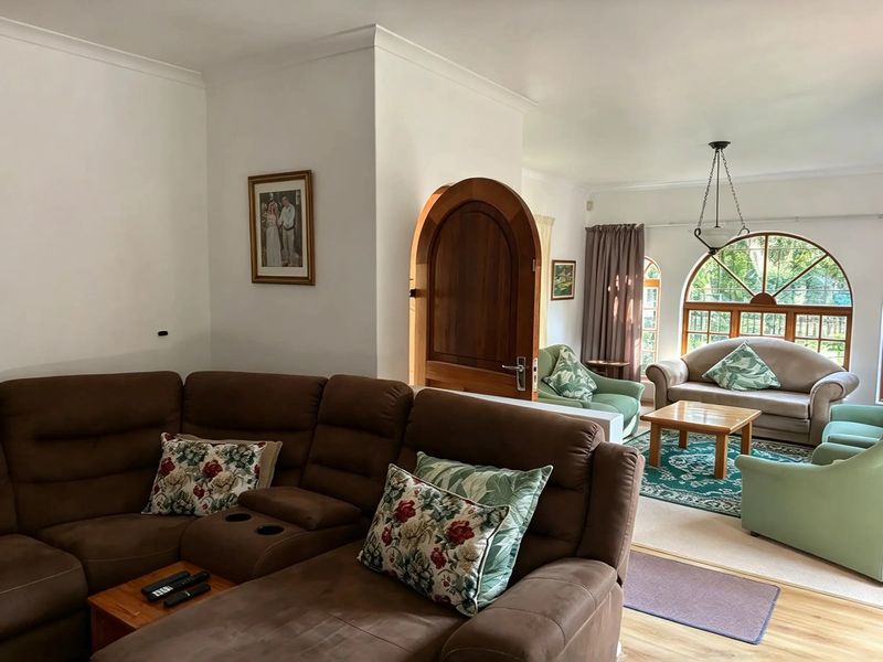 Spacious living area featuring an arched timber door, large arched window, and neutral finishes, offering a comfortable and inviting atmosphere.
