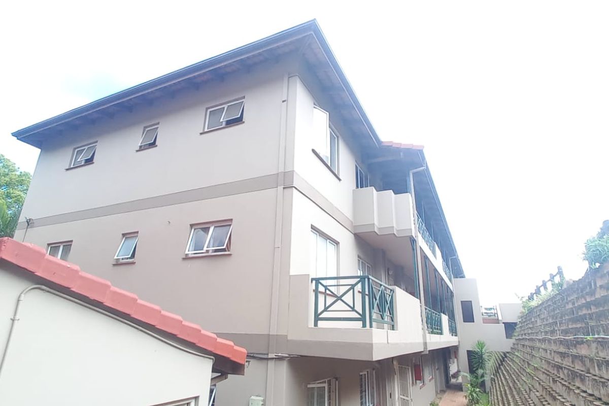 Rear elevation of a multi-story flat complex featuring balconies, casement windows, and a tiered retaining wall structure.