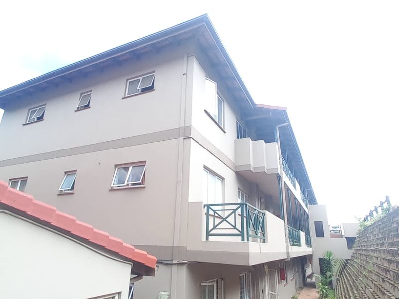 Rear elevation of a multi-story flat complex featuring balconies, casement windows, and a tiered retaining wall structure.