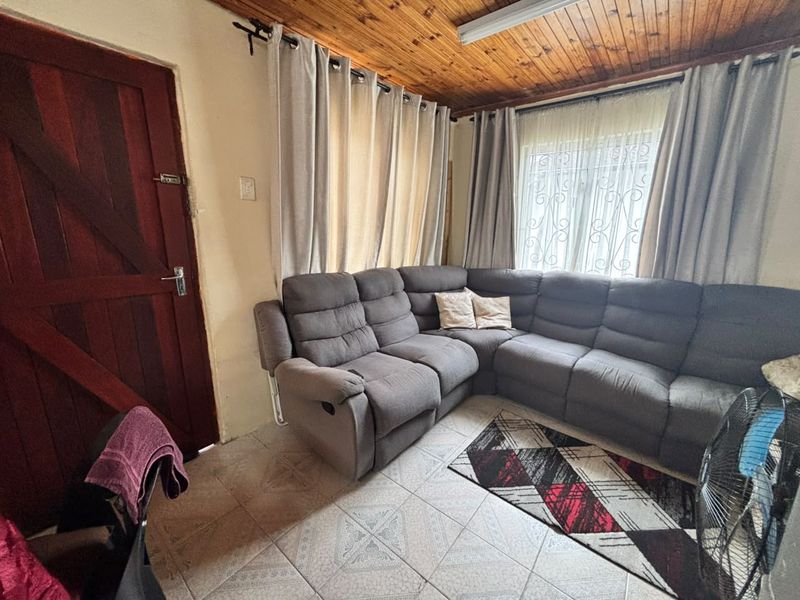 A living room featuring tiled flooring and a timber tongue and groove ceiling, providing a functional space with potential for modern updates.