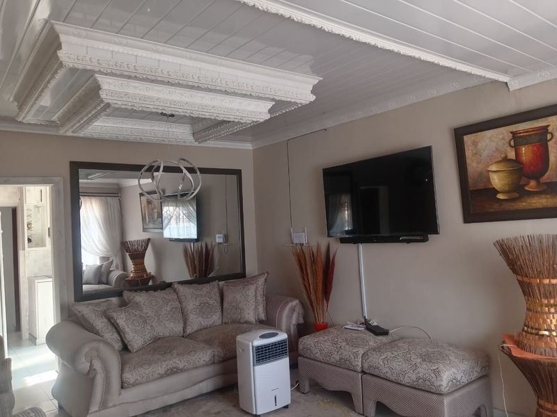 A living room featuring an ornate coffered ceiling, large wall mirror, and neutral wall tones, providing a classic foundation for interior updates.