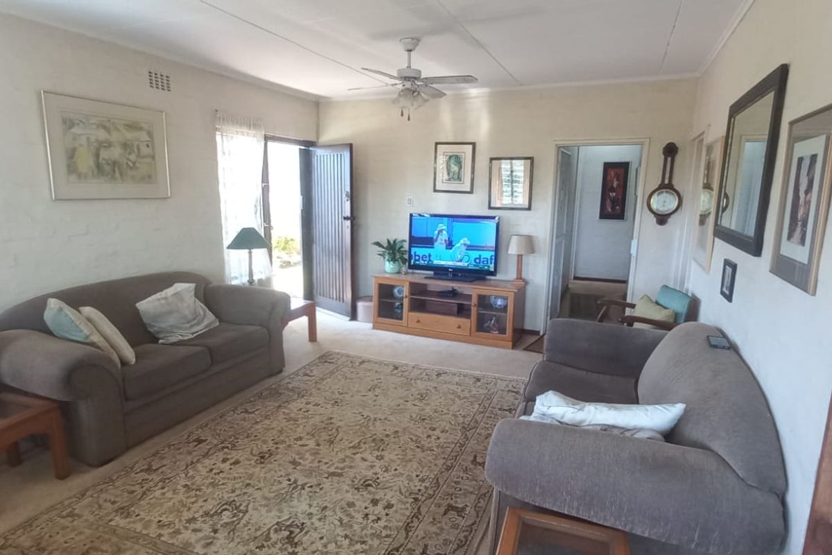 A comfortable living room featuring a ceiling fan and direct access to the exterior through a timber door.