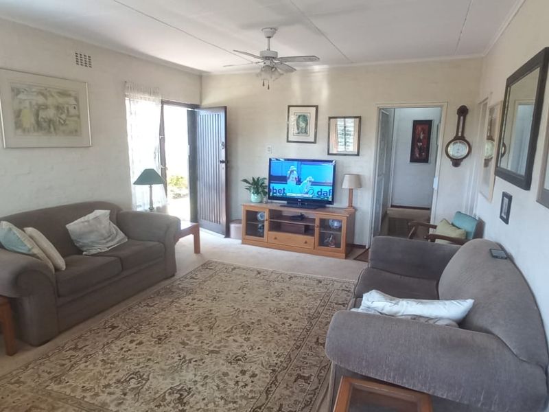 A comfortable living room featuring a ceiling fan and direct access to the exterior through a timber door.