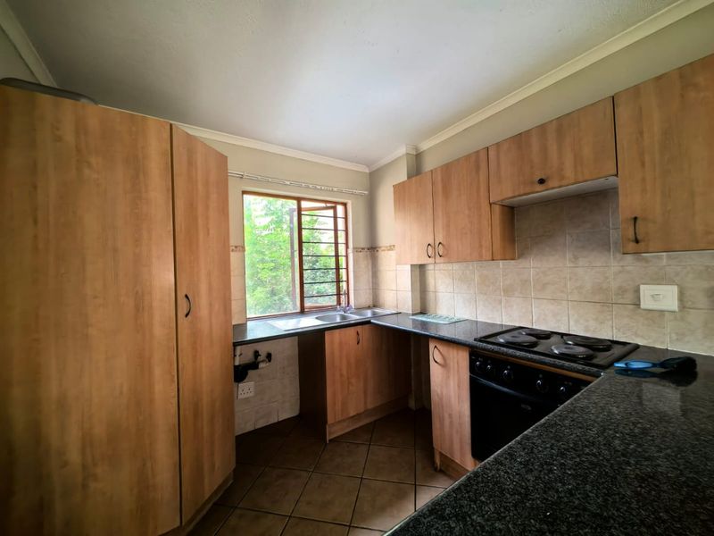 A functional kitchen featuring laminate cabinetry, granite countertops, a built-in oven and hob, and tiled flooring, offering a practical layout for daily use.