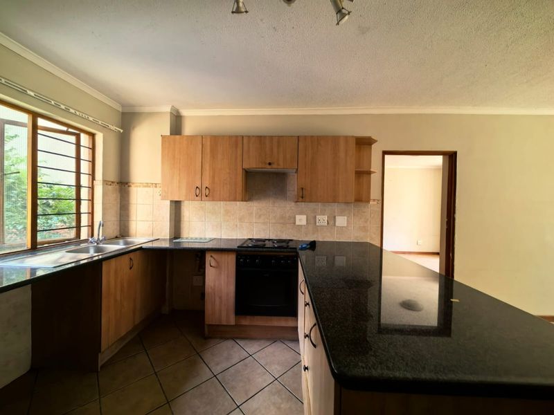 A functional kitchen featuring laminate cabinetry, granite countertops, a built-in oven with gas hob, and tiled flooring, offering a practical layout for renovation.