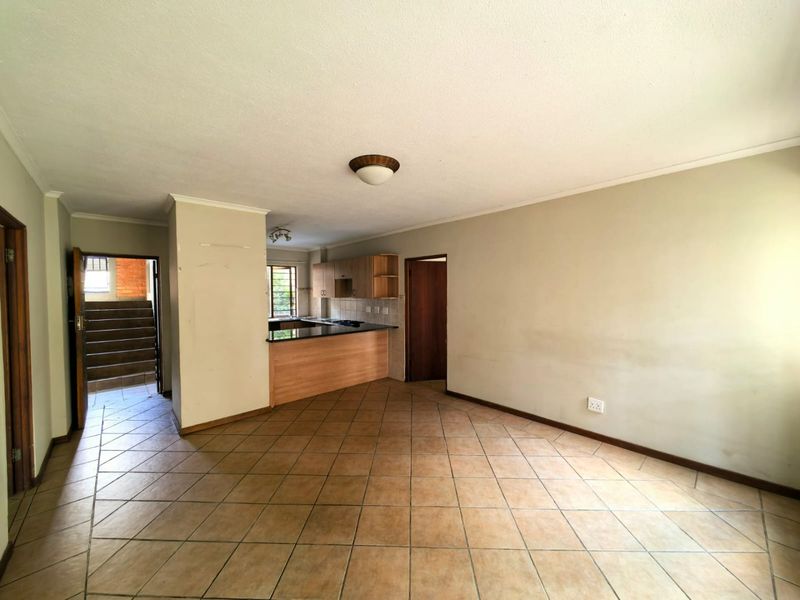 Spacious open-plan living area featuring tiled flooring and a functional kitchen with built-in cabinetry and granite countertops.