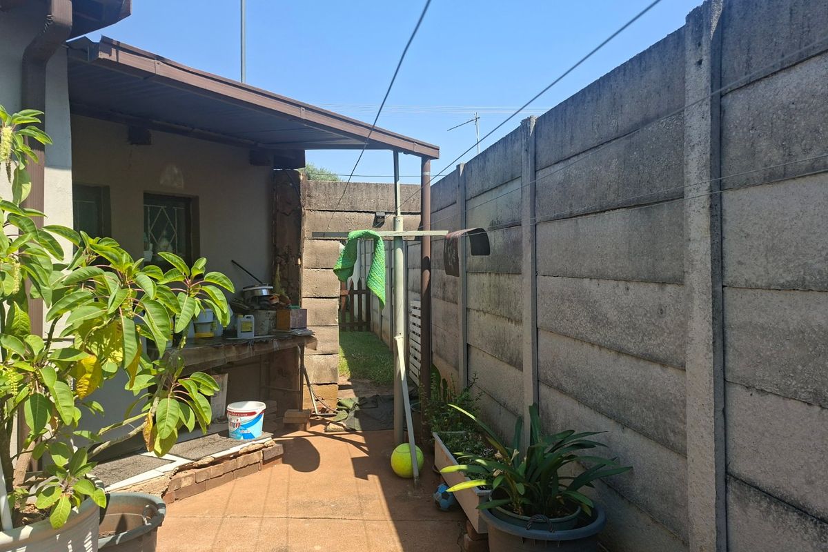 A rear exterior area featuring a covered patio, concrete boundary wall, and a fixed washing line, offering potential for outdoor improvement.