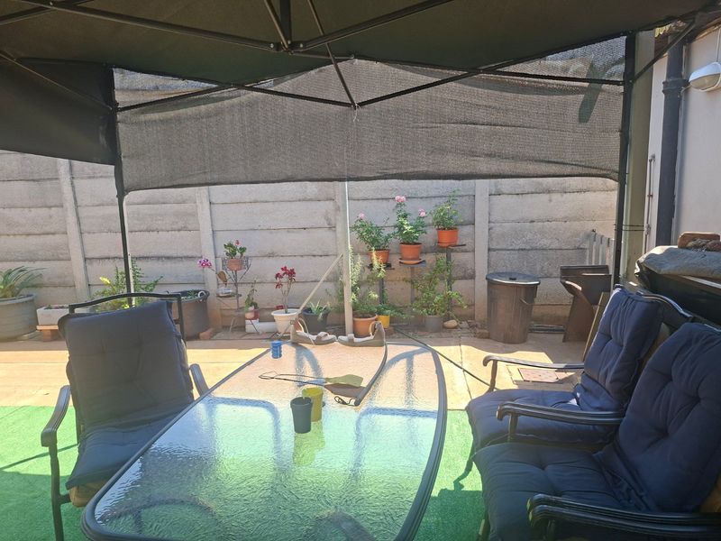 A covered outdoor patio area featuring a precast concrete boundary wall and paved flooring, suitable for outdoor dining and relaxation.